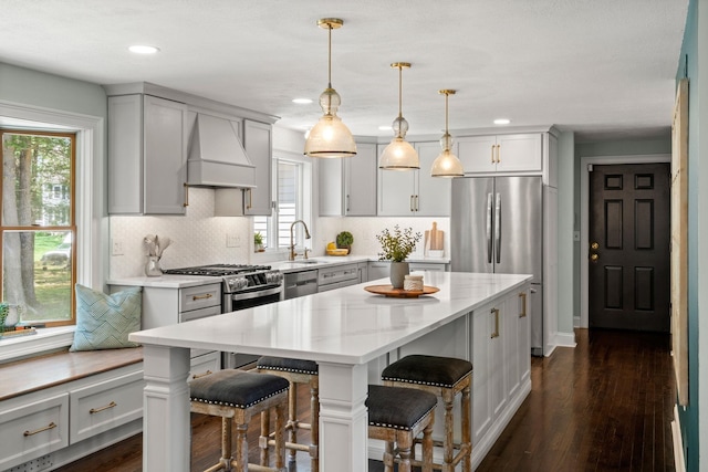 kitchen featuring a sink, custom exhaust hood, a center island, tasteful backsplash, and dark wood finished floors