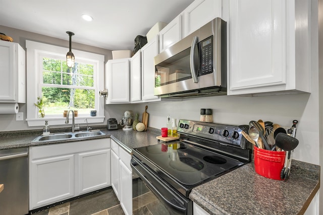 kitchen with stainless steel appliances, a sink, dark countertops, white cabinets, and recessed lighting
