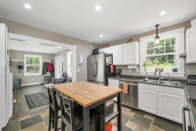 kitchen featuring stainless steel appliances, a sink, white cabinets, recessed lighting, and pendant lighting