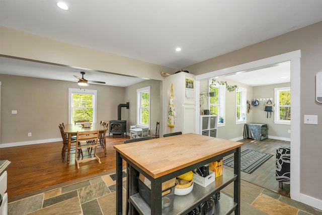 dining room with a wood stove, baseboards, recessed lighting, and wood finished floors