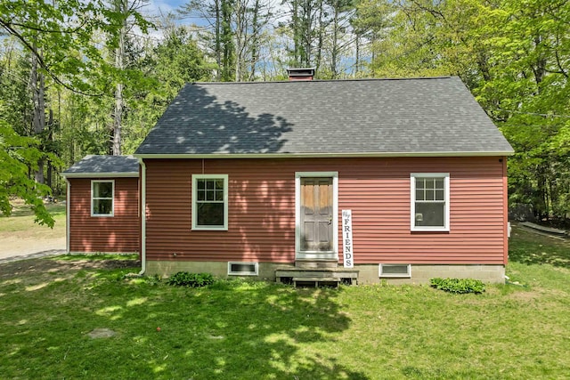 back of house with a lawn, a shingled roof, entry steps, and a chimney