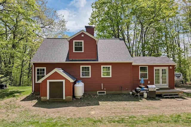 rear view of property featuring french doors, roof with shingles, a chimney, and a yard