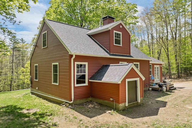 view of property exterior featuring a shingled roof and a chimney