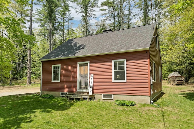 back of house with a shingled roof, a lawn, and entry steps
