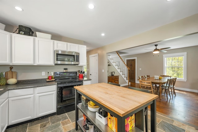kitchen with stainless steel microwave, black electric range, white cabinets, recessed lighting, and dark countertops