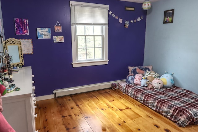 bedroom with a baseboard radiator, baseboards, and wood-type flooring