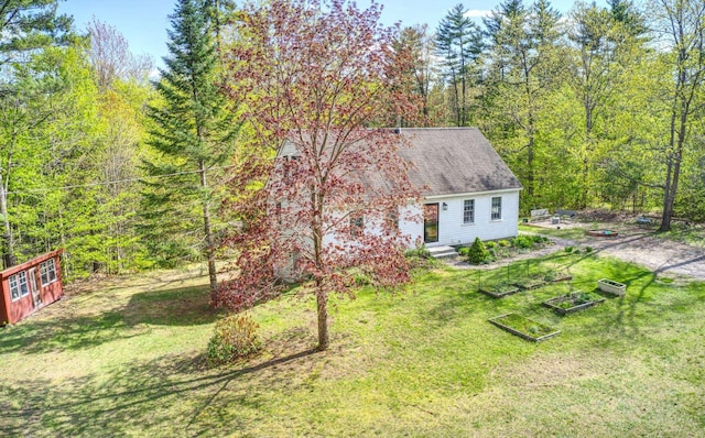 view of grassy yard with a garden and a forest view