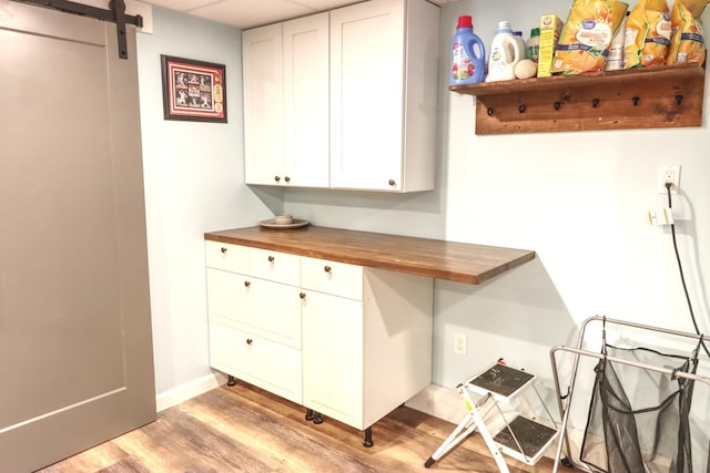 bar featuring light wood-style floors, a barn door, and baseboards