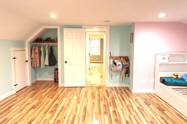 unfurnished bedroom featuring wood finished floors, baseboard heating, a closet, lofted ceiling, and recessed lighting