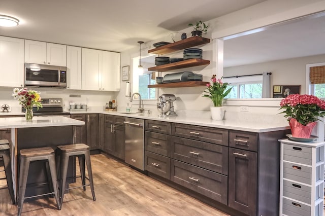 kitchen featuring stainless steel appliances, a sink, light countertops, and white cabinetry