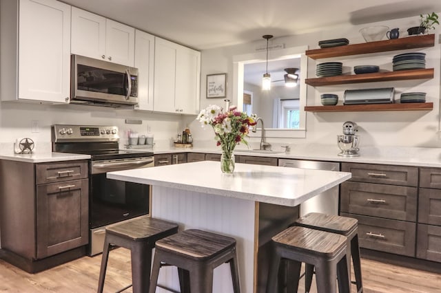 kitchen with stainless steel appliances, a sink, a breakfast bar, light wood-style flooring, and light countertops