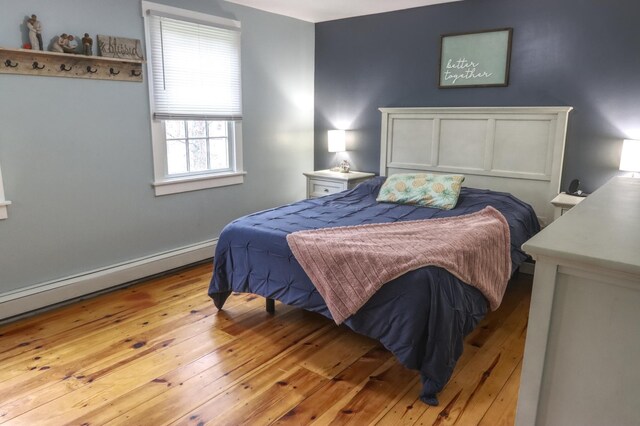 bedroom with light wood-type flooring and a baseboard radiator