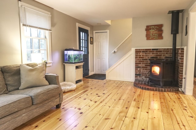 living area with hardwood / wood-style floors, a wood stove, a wainscoted wall, and stairway