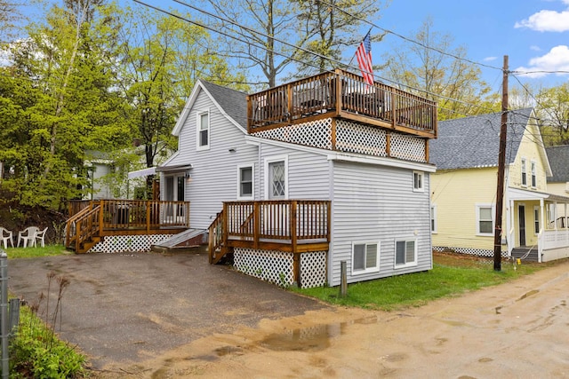 back of property with a deck, a shingled roof, and a balcony
