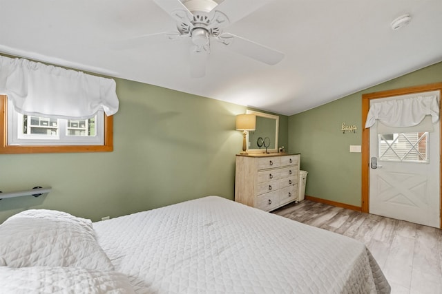 bedroom featuring lofted ceiling, multiple windows, ceiling fan, wood finished floors, and baseboards