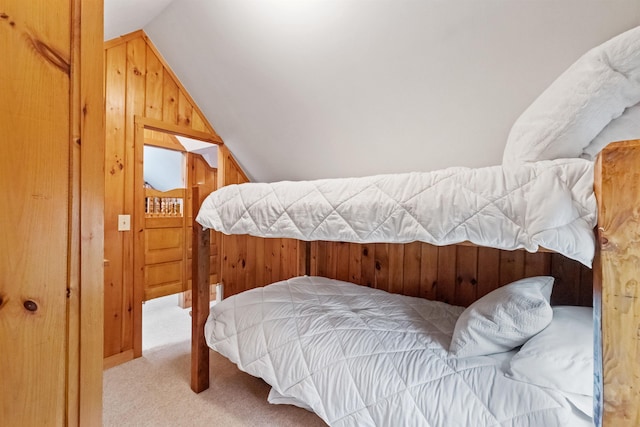carpeted bedroom with lofted ceiling and wood walls