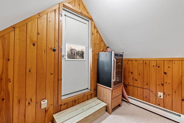 additional living space with a baseboard radiator, lofted ceiling, wood walls, and light carpet