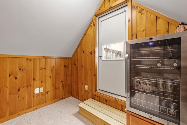 bonus room featuring beverage cooler, vaulted ceiling, wood walls, and carpet flooring