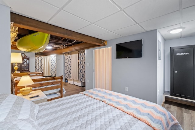 bedroom with wood finished floors and a paneled ceiling