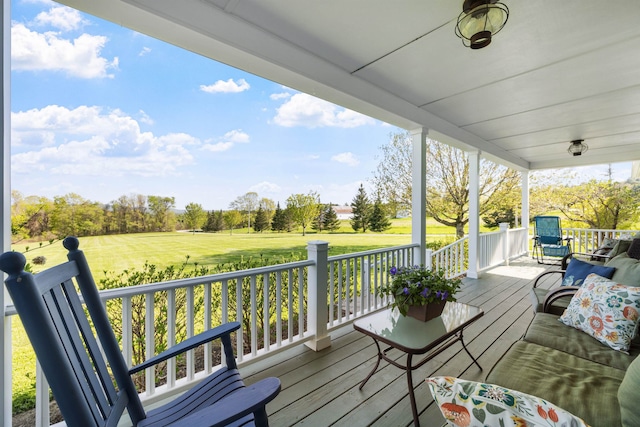 wooden deck featuring covered porch and a lawn
