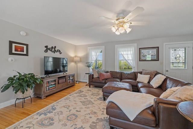 living room featuring light wood-style floors, ceiling fan, and baseboards