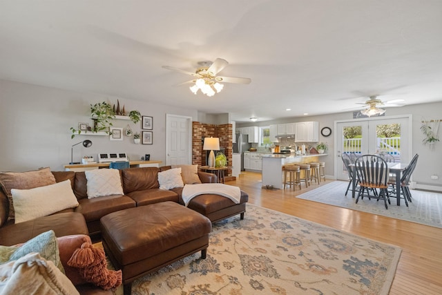 living room featuring a ceiling fan, light wood-style flooring, and a baseboard radiator