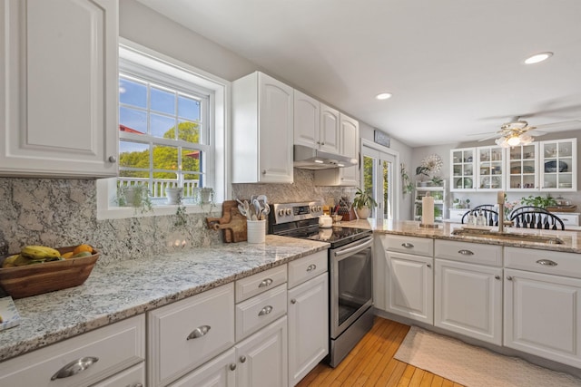 kitchen featuring electric stove, under cabinet range hood, a sink, ceiling fan, and white cabinets