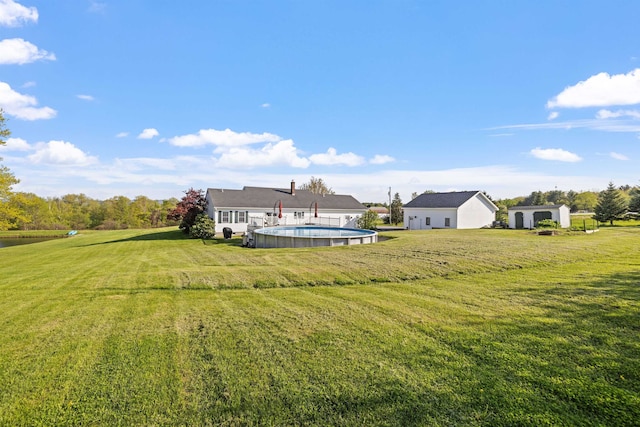 view of grassy yard with an outdoor pool, an outbuilding, a storage unit, and a water view