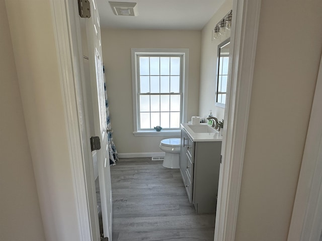 bathroom with vanity, toilet, wood finished floors, and baseboards