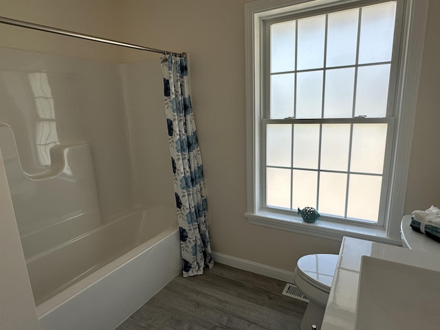 bathroom with toilet, wood finished floors, shower / bath combo with shower curtain, and baseboards