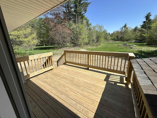 wooden terrace with a lawn and view of wooded area