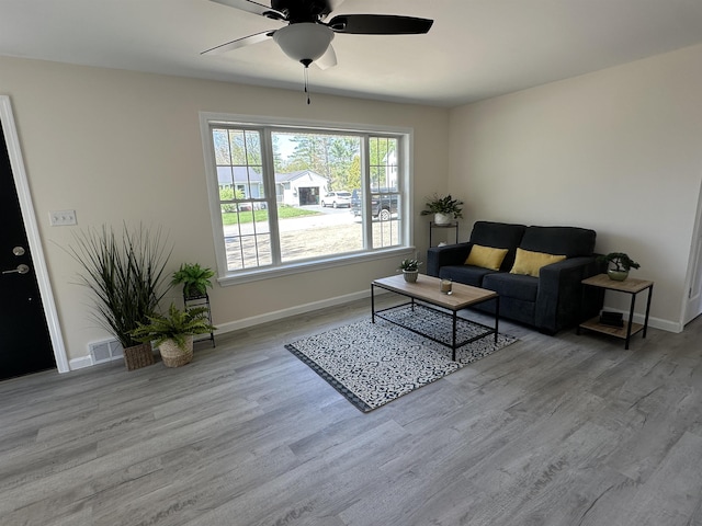 living area featuring wood finished floors, a ceiling fan, and baseboards
