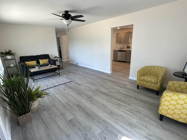 living area featuring light wood finished floors, ceiling fan, and baseboards