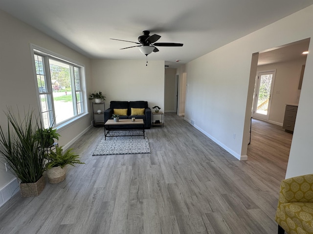 living area with healthy amount of natural light, wood finished floors, and a ceiling fan
