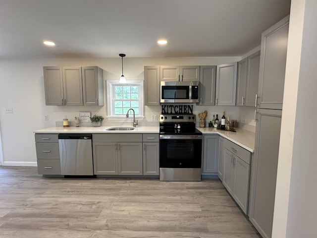kitchen featuring appliances with stainless steel finishes, a sink, gray cabinetry, recessed lighting, and light countertops