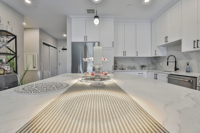 kitchen with appliances with stainless steel finishes, backsplash, white cabinetry, light stone counters, and recessed lighting