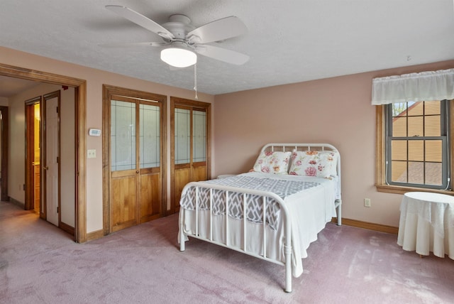 carpeted bedroom featuring baseboards, a ceiling fan, and multiple closets