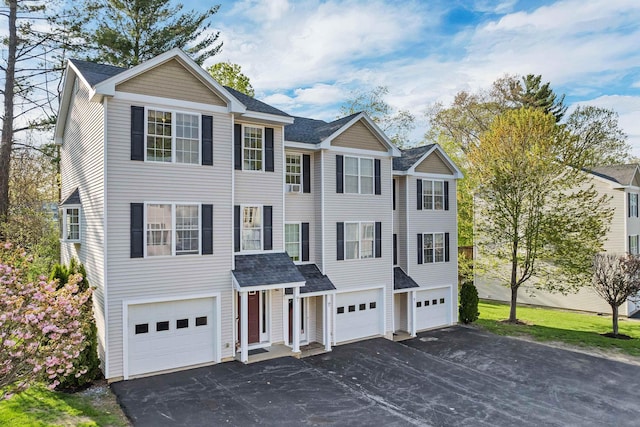 view of front of house with an attached garage, driveway, and roof with shingles