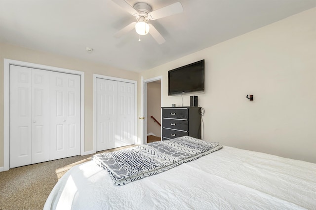 carpeted bedroom with two closets, baseboards, and a ceiling fan