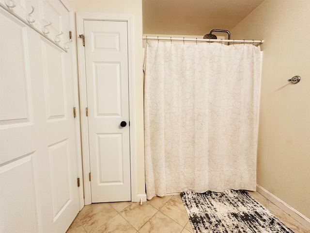 bathroom with tile patterned floors, baseboards, and curtained shower