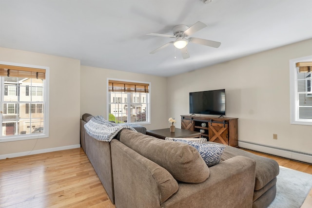 living room featuring light wood-style floors, a baseboard heating unit, ceiling fan, and baseboards
