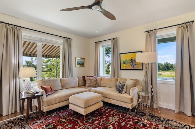 living room featuring wood finished floors, baseboards, and ceiling fan