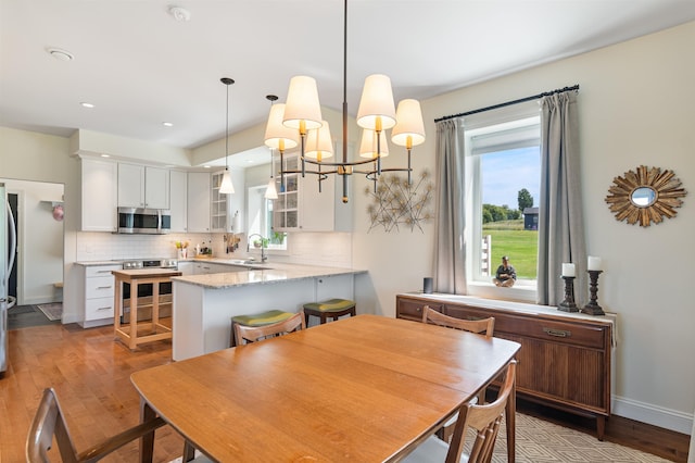 dining space with wood finished floors, healthy amount of natural light, a chandelier, and recessed lighting