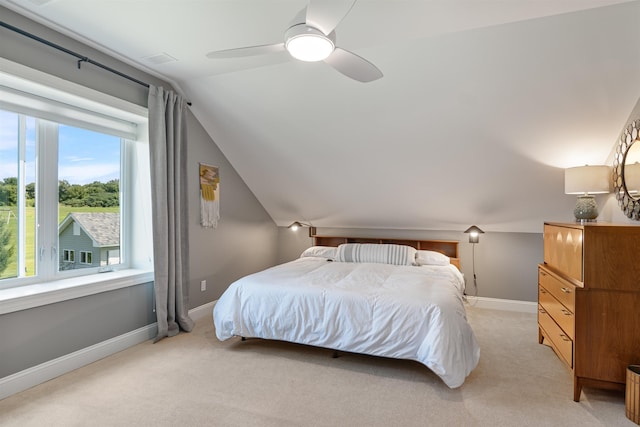 bedroom featuring light colored carpet, vaulted ceiling, baseboards, and a ceiling fan