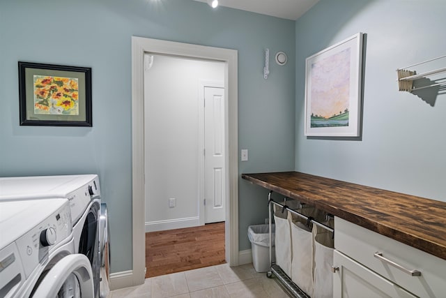 laundry area featuring washer and clothes dryer, cabinet space, baseboards, and light tile patterned flooring
