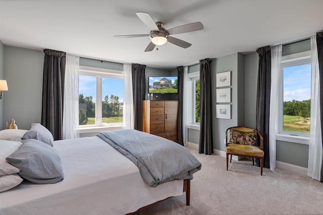 bedroom featuring light colored carpet, baseboards, and a ceiling fan