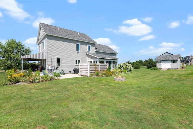 rear view of house featuring a patio area, a shingled roof, an outdoor fire pit, and a lawn
