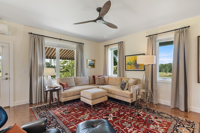 living area with wood finished floors, a ceiling fan, and baseboards