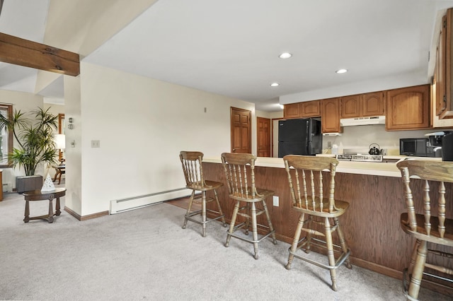 kitchen featuring black appliances, a baseboard heating unit, under cabinet range hood, light countertops, and light colored carpet
