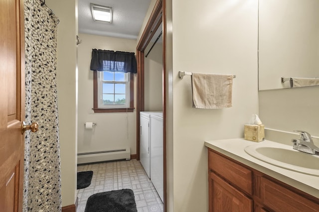 bathroom featuring a baseboard heating unit, separate washer and dryer, and vanity